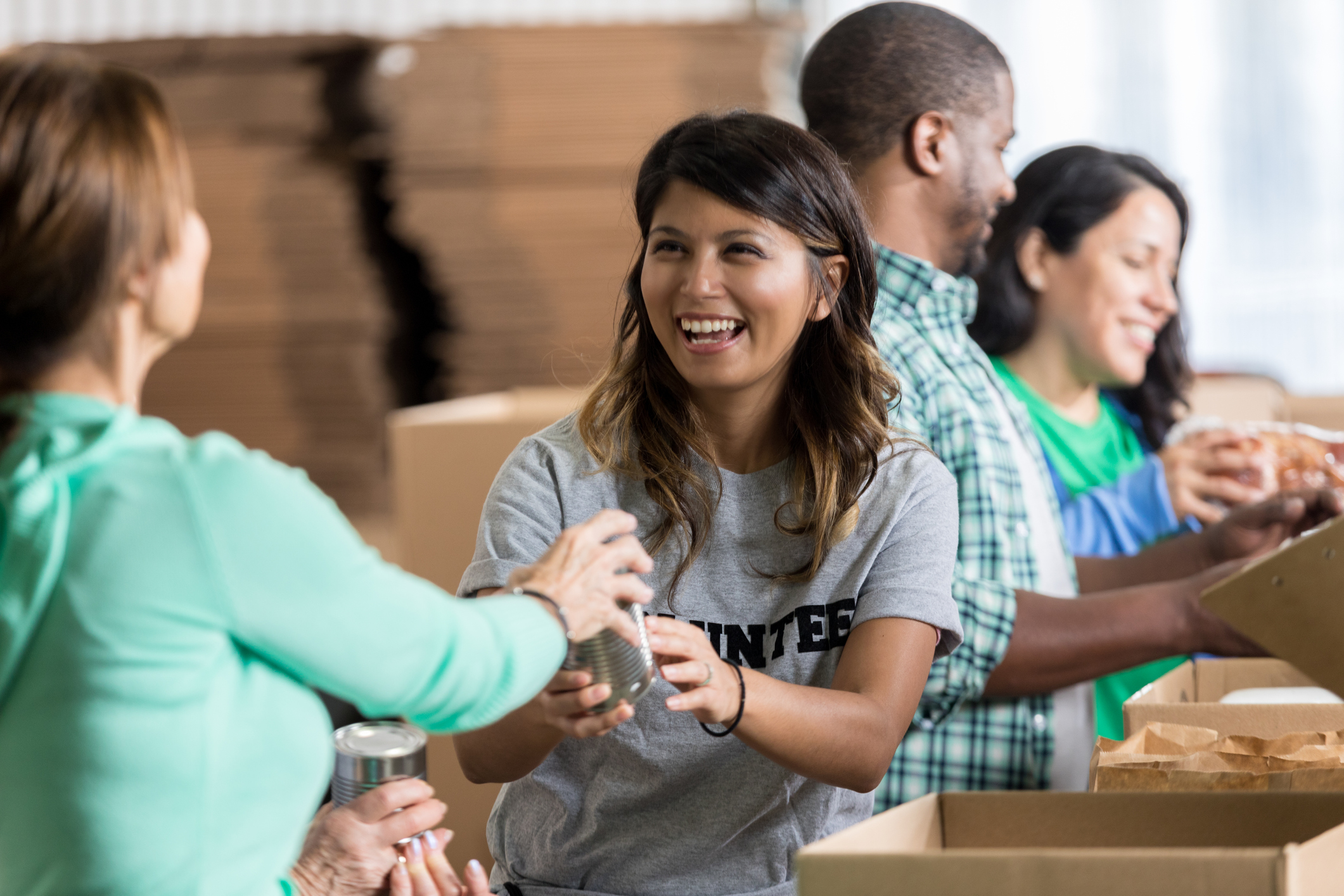 Cheerful female volunteer accepts a canned food donation during community food drive.